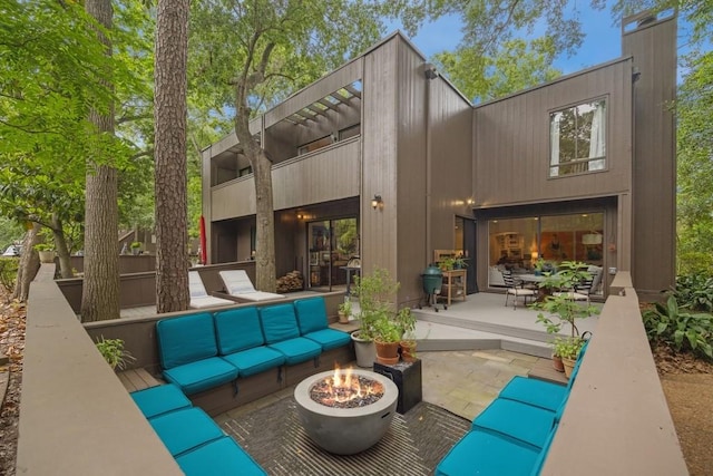 rear view of property featuring a patio, an outdoor living space with a fire pit, and a chimney