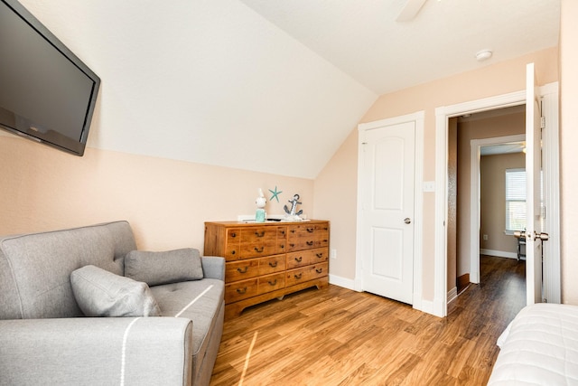 living area featuring a ceiling fan, baseboards, vaulted ceiling, and light wood-style floors
