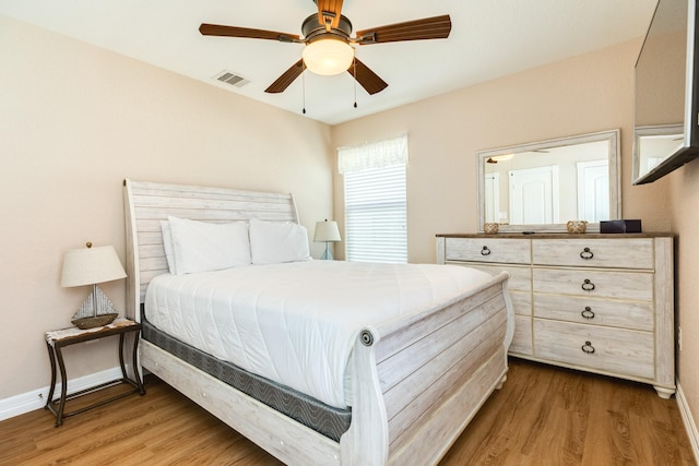 bedroom featuring wood finished floors, visible vents, ceiling fan, and baseboards