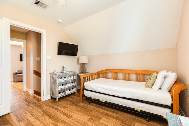 bedroom with visible vents, ceiling fan, baseboards, vaulted ceiling, and wood finished floors