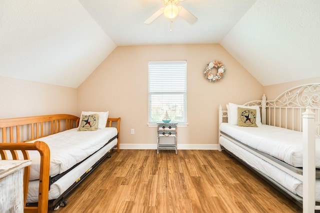 bedroom with a ceiling fan, light wood-style flooring, vaulted ceiling, and baseboards