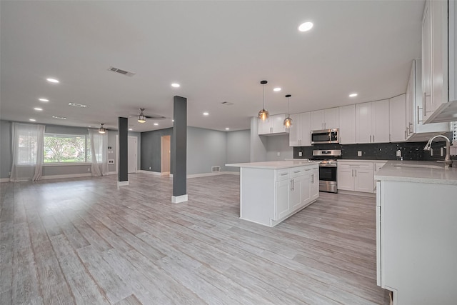 kitchen with baseboards, open floor plan, appliances with stainless steel finishes, and a sink