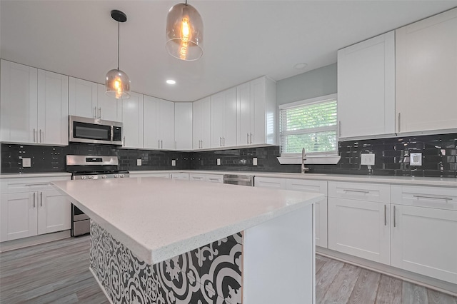 kitchen with light wood-type flooring, backsplash, a center island, and appliances with stainless steel finishes