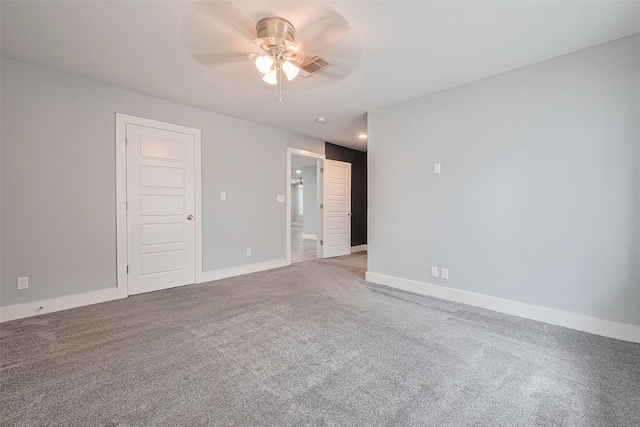 carpeted spare room with visible vents, a ceiling fan, and baseboards