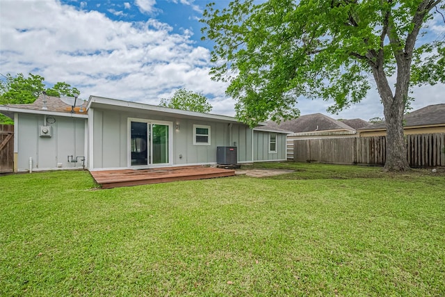 rear view of house featuring board and batten siding, fence, central air condition unit, a wooden deck, and a lawn