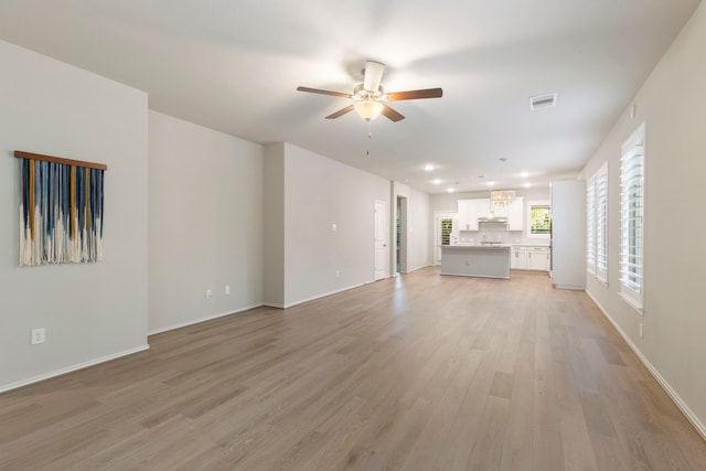 549 Timber Voyage Ct, Conroe, TX 77304 - unfurnished living room featuring baseboards, visible vents, ceiling fan with notable chandelier, and light wood-style floors