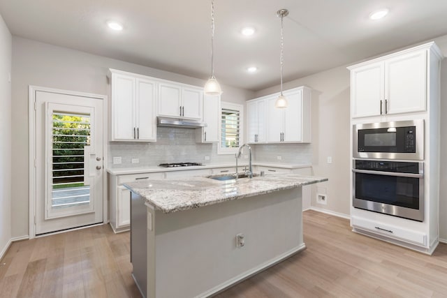 549 Timber Voyage Ct, Conroe, TX 77304 - kitchen with oven, gas cooktop, built in microwave, under cabinet range hood, and a sink