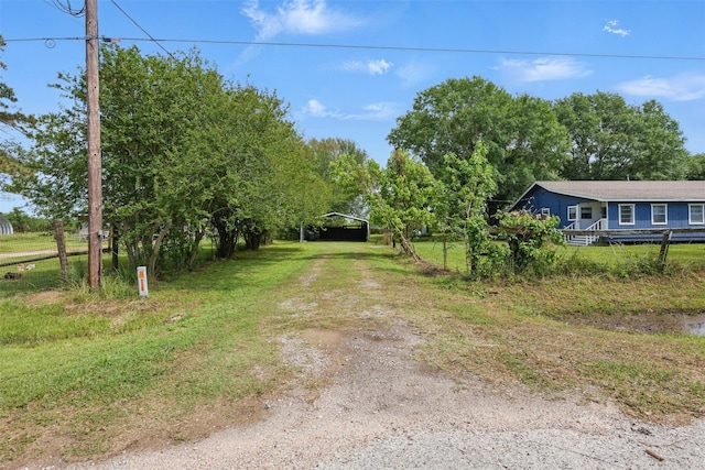 view of yard with a carport and dirt driveway