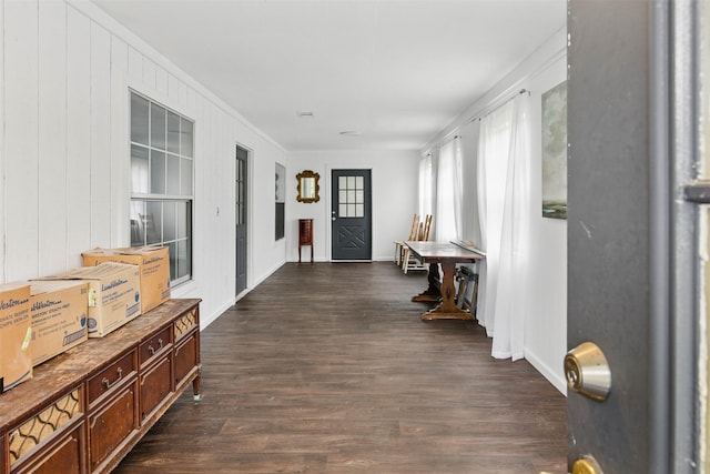 corridor with ornamental molding, baseboards, and dark wood finished floors