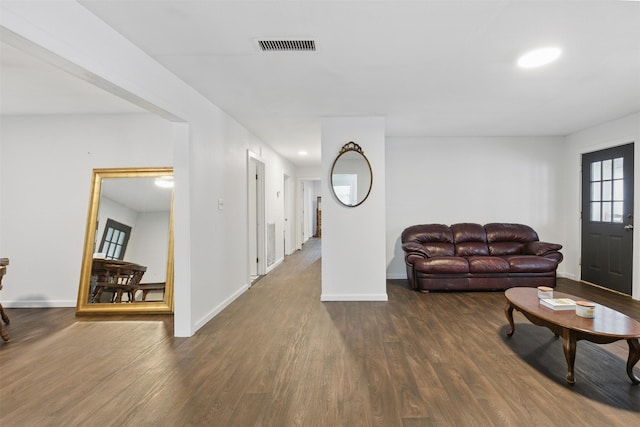 living room featuring dark wood-style flooring, visible vents, and baseboards