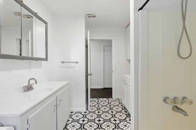 bathroom with baseboards, visible vents, walk in shower, and vanity