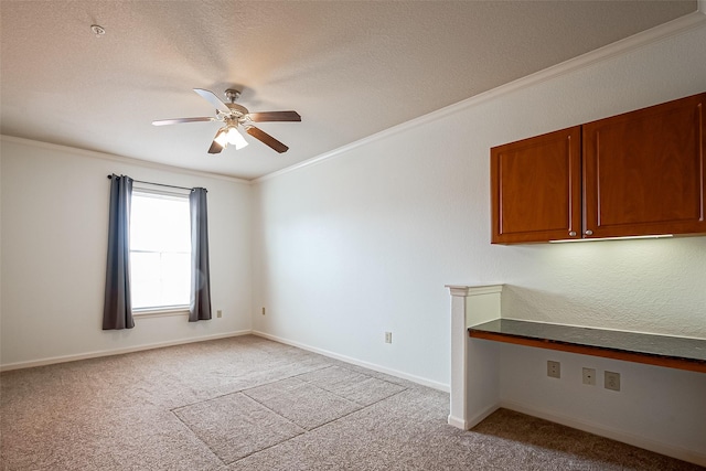 spare room with a ceiling fan, baseboards, crown molding, and light carpet