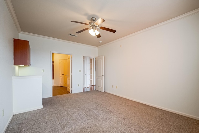 spare room featuring carpet, a ceiling fan, ornamental molding, and baseboards