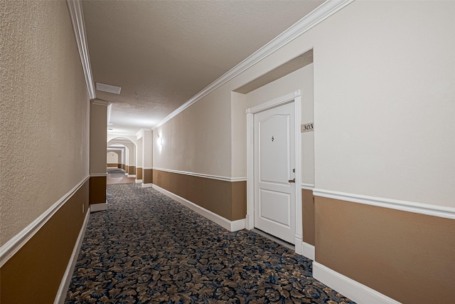 hallway featuring crown molding, carpet flooring, and arched walkways
