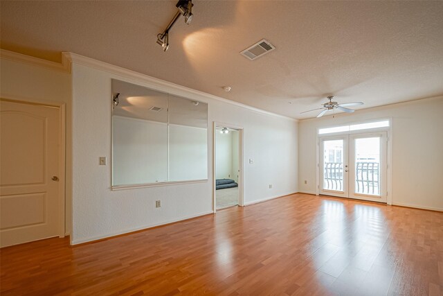 empty room with ceiling fan, visible vents, light wood-style flooring, ornamental molding, and a textured ceiling