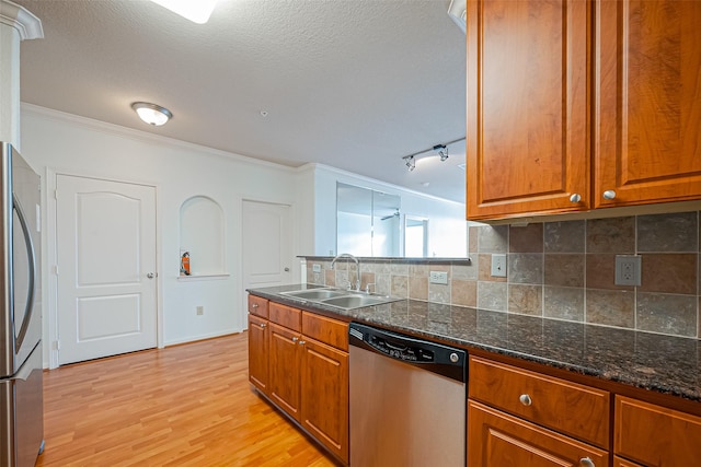kitchen with brown cabinets, a sink, appliances with stainless steel finishes, and tasteful backsplash