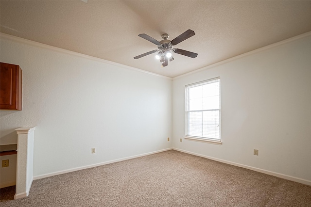spare room featuring ornamental molding, a ceiling fan, carpet flooring, and baseboards