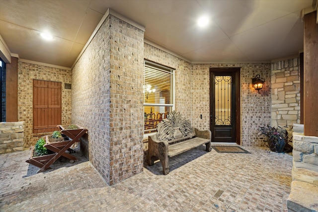 property entrance with a porch and brick siding