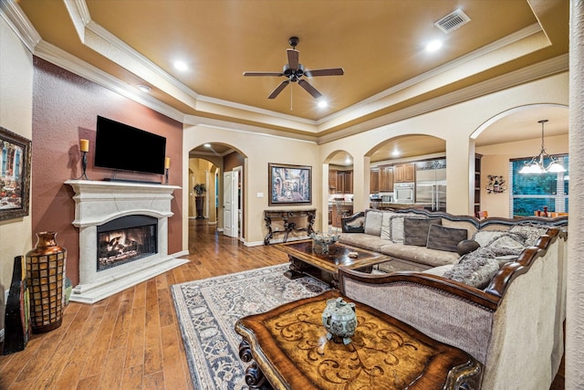 36927 Anglers Way, Pinehurst, TX 77362 - living area with a tray ceiling, arched walkways, ceiling fan, wood-type flooring, and ornamental molding