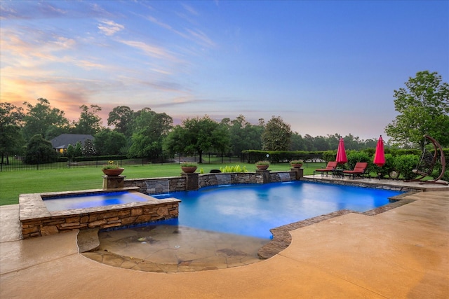 pool at dusk featuring a lawn, a pool with connected hot tub, a patio, and a fenced backyard