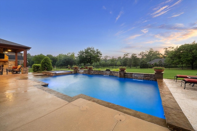 view of pool with a lawn, fence, a pool with connected hot tub, and a patio area