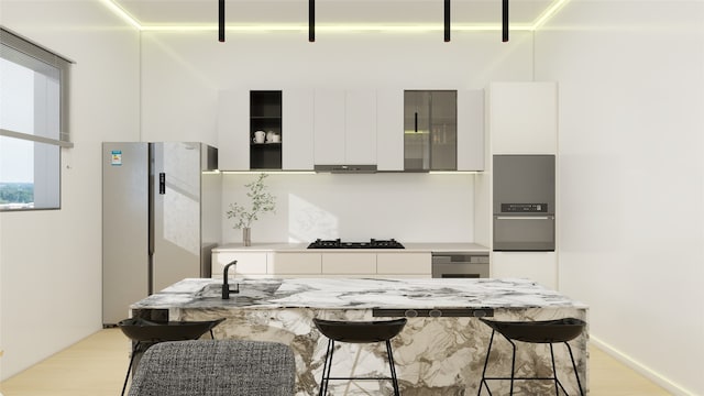 7125 England St, Houston, TX 77021 - kitchen featuring white cabinets, a breakfast bar, freestanding refrigerator, under cabinet range hood, and modern cabinets