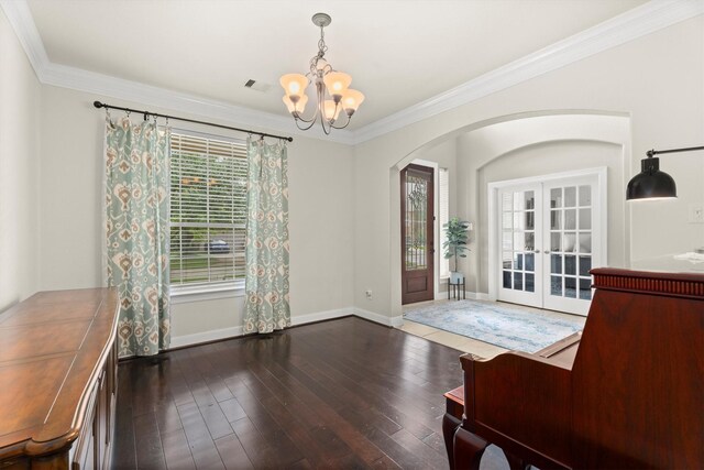 foyer with crown molding, arched walkways, a notable chandelier, and hardwood / wood-style floors