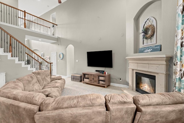 1619 Julia Park Dr, Spring, TX 77386 - tiled living room with arched walkways, a towering ceiling, stairway, a premium fireplace, and baseboards
