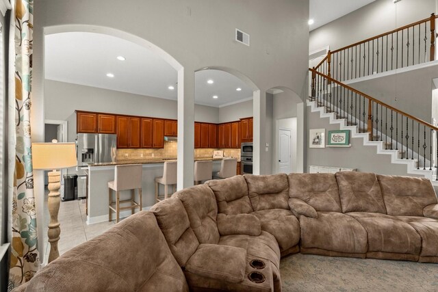 living area with arched walkways, recessed lighting, and a towering ceiling