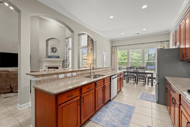 kitchen featuring ornamental molding, light tile patterned flooring, a center island with sink, a sink, and stainless steel appliances