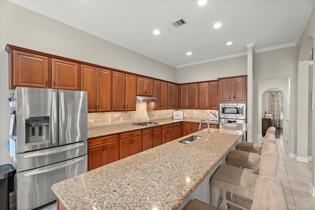 kitchen with visible vents, appliances with stainless steel finishes, arched walkways, a sink, and under cabinet range hood