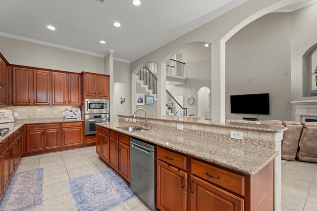 kitchen featuring light tile patterned flooring, appliances with stainless steel finishes, a sink, decorative backsplash, and ornamental molding
