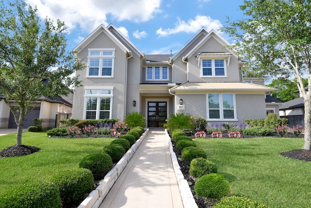 view of front facade with a front lawn, a standing seam roof, metal roof, stucco siding, and french doors