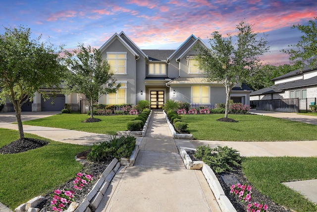 traditional-style house featuring a front yard, a standing seam roof, stucco siding, french doors, and fence