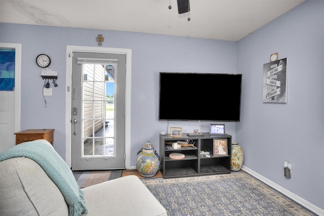 living area featuring a ceiling fan and baseboards