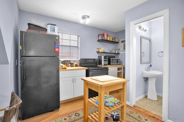 kitchen with black appliances, light wood finished floors, open shelves, and white cabinetry