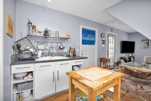 interior space with light wood-type flooring, decorative backsplash, and a sink
