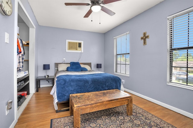 bedroom featuring wood finished floors, baseboards, and multiple windows