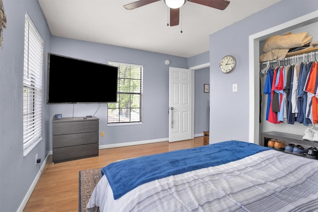 bedroom with a closet, a ceiling fan, wood finished floors, and baseboards
