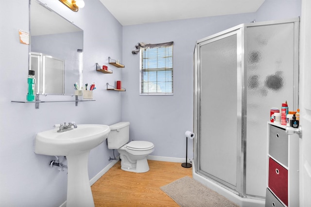 full bathroom featuring wood finished floors, toilet, a stall shower, and baseboards