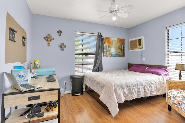 bedroom featuring a ceiling fan, multiple windows, wood finished floors, and baseboards