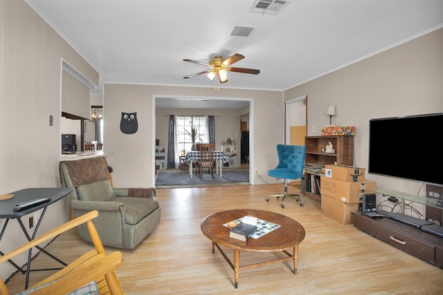living area with visible vents, wood finished floors, ceiling fan, and ornamental molding