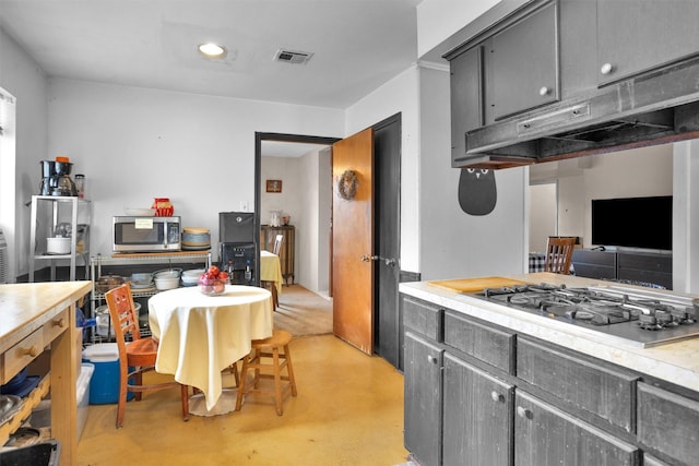 kitchen with gray cabinets, gas cooktop, under cabinet range hood, and stainless steel microwave