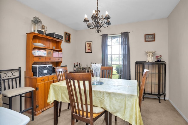 dining room featuring a chandelier, baseboards, and light carpet