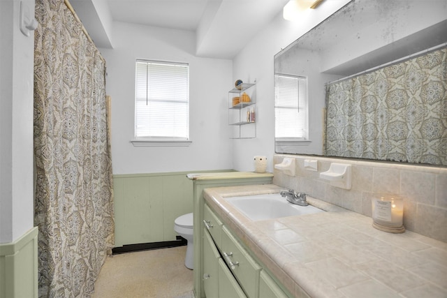 bathroom with toilet, a wainscoted wall, vanity, and a healthy amount of sunlight