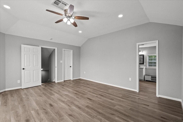 unfurnished bedroom with lofted ceiling, visible vents, baseboards, recessed lighting, and wood finished floors