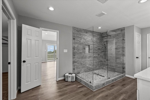 bathroom featuring baseboards, visible vents, wood finished floors, and a shower stall