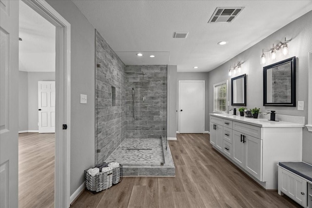 full bath with visible vents, wood finished floors, a walk in shower, and a sink