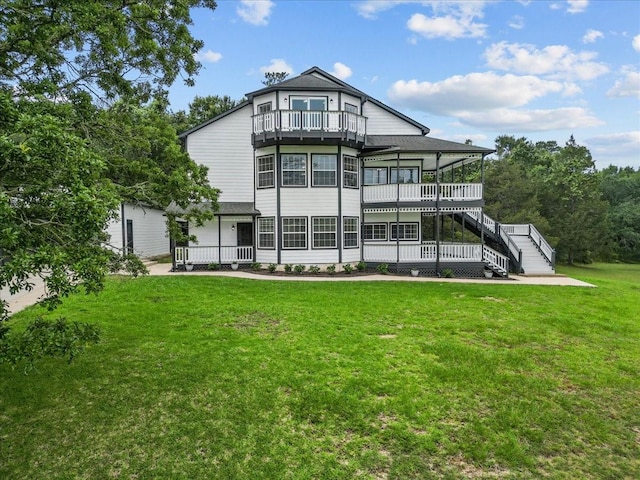 rear view of property featuring a lawn, stairway, and a balcony