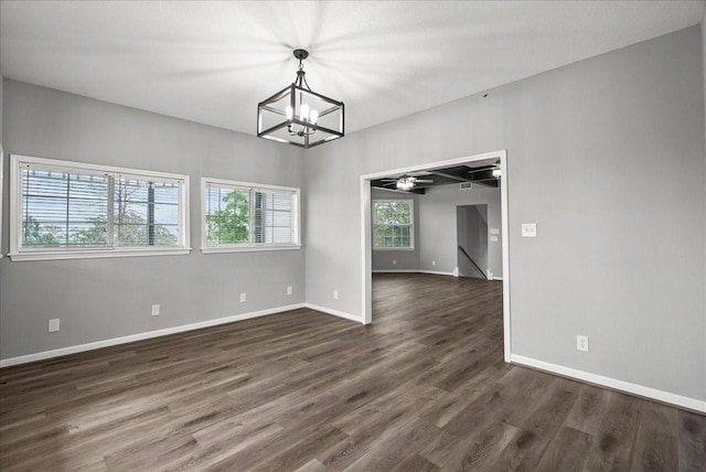 unfurnished room with a chandelier, dark wood-style floors, and baseboards
